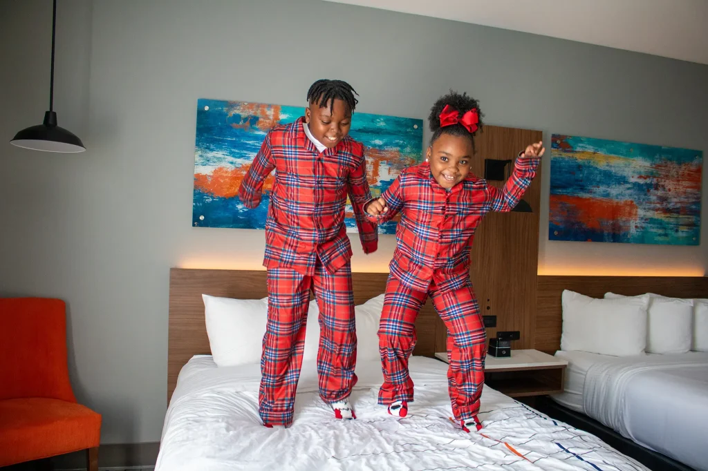 kids in holiday pajamas jumping on the hotel bed