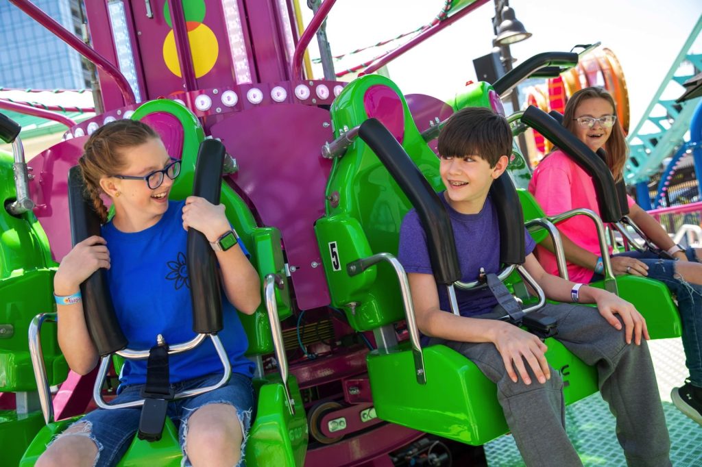 a boy and girl sitting on a twirling thrill ride at the funplex myrtle beach